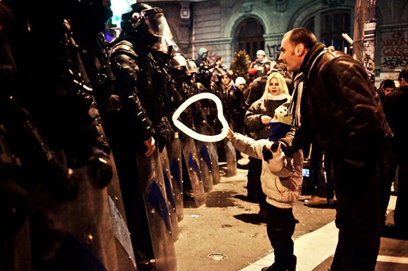 Ein rumänisches Kind verschenkt sein Luftballonherz einem Polizisten, 2012 in Bukarest.&nbsp;