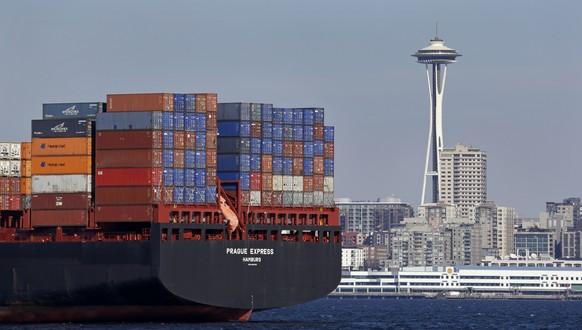 FILE - In this Feb. 15, 2015 file photo, the Space Needle towers in the background beyond a container ship anchored in Elliott Bay near downtown Seattle. The U.S. trade deficit fell in September 2016  ...
