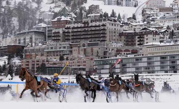 ST MORITZ, SWITZERLAND - FEBRUARY 08: Competitors of the GP Swiss International Air Lines Trotting Race of the White Turf St Moritz seen in front of the St Moritz skyline on February 8, 2015 in St Mor ...