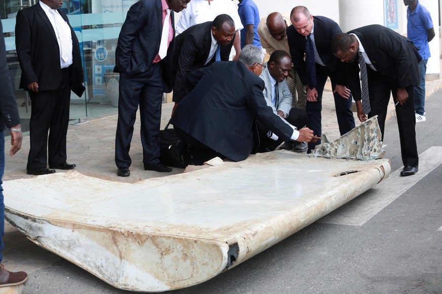 Ministry of Transport Malaysian Senior Accident investigator Aslam Basha Kham (C) talks to other officials inspecting a wing suspected to be a part of missing Malaysia Airlines jet MH370 discovered on ...