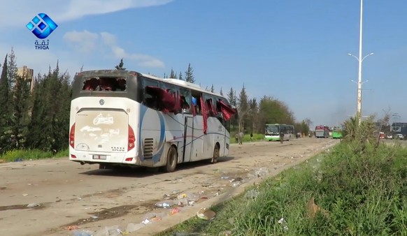 epa05909735 A handout photo made available by Thiqa News Agency (TNA) showing a damaged bus at the scene of a car bomb attack that targeted buses evacuating civilians from besieged towns, al-Rashideen ...