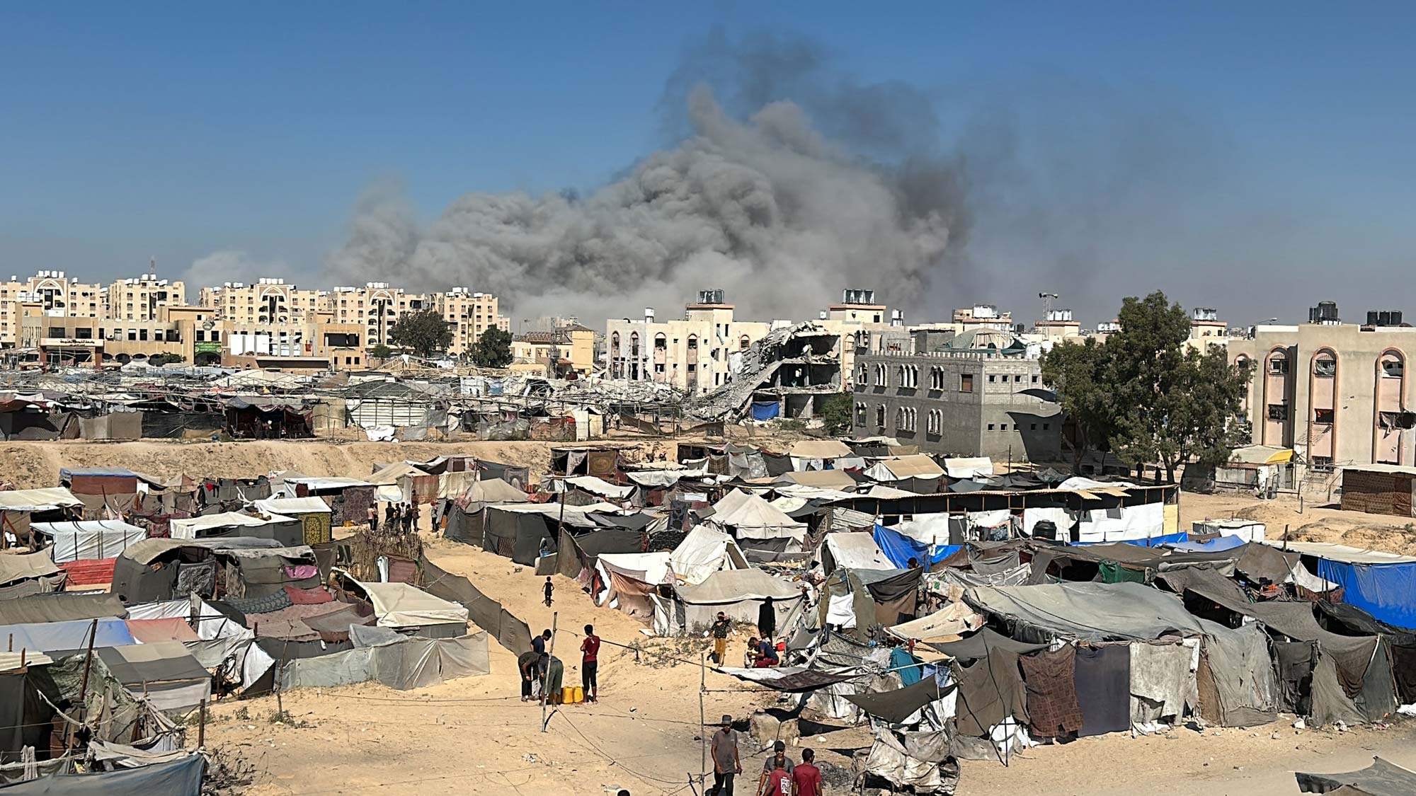 Zelte bei Hamad-Stadt, Rauch im Hintergrund nach einem israelischen Angriff