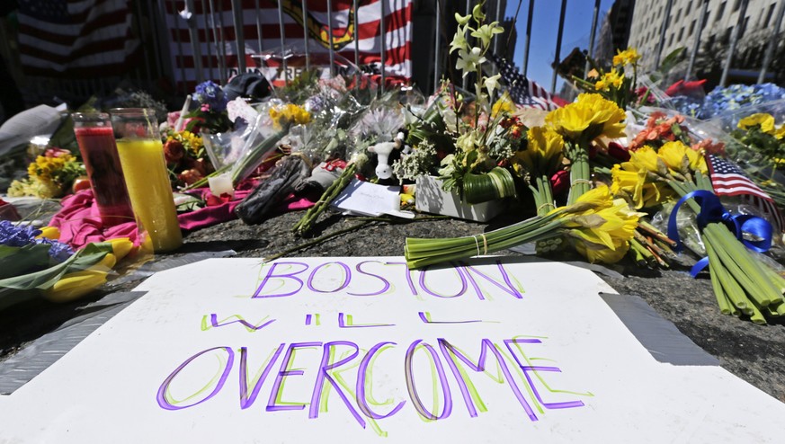 Flowers and signs adorn a barrier, two days after two explosions killed three and injured hundreds, near the of finish line of the Boston Marathon at a makeshift memorial for victims and survivors of  ...