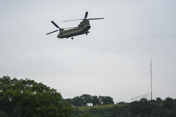 A sign for Camp Mystic is seen on a hill as a heavy-lift military helicopter flies by over the Guadalupe River, Sunday, July 6, 2025, in Hunt, Texas, after a flash flood swept through the area. (AP Ph ...