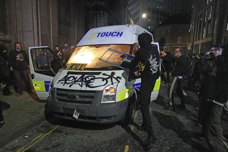 Protesters set fire to a vandalized police van outside Bridewell Police Station, in Bristol, England, Sunday March 21, 2021, as people took part in a protest demonstrating against the Police and Crime ...