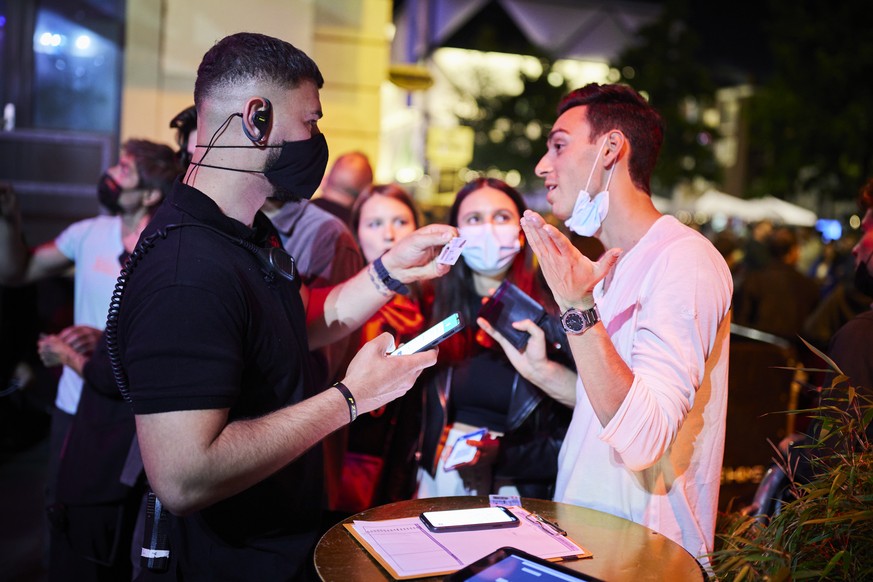 A security staff member of the MAD (Moulin a Danse) night club scans the QR code of a COVID-19 certificate allowing entry in newly reopened nightclubs in Lausanne, Switzerland, late Friday, June 25, 2 ...