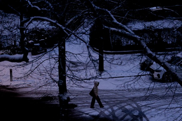 epa12623542 A pedestrian walks through the Lichterfelde district in western Berlin, Germany, 03 January 2026. A major power outage struck western Berlin early 03 January after a cable bridge over the  ...