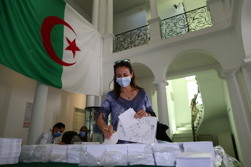 epa09259590 An Algerian woman picks up ballot papers before voting during parliamentary election at the Algerian Consulate General in Tunis,Tunisia on 10 June 2021. The Algerian legislative elections  ...