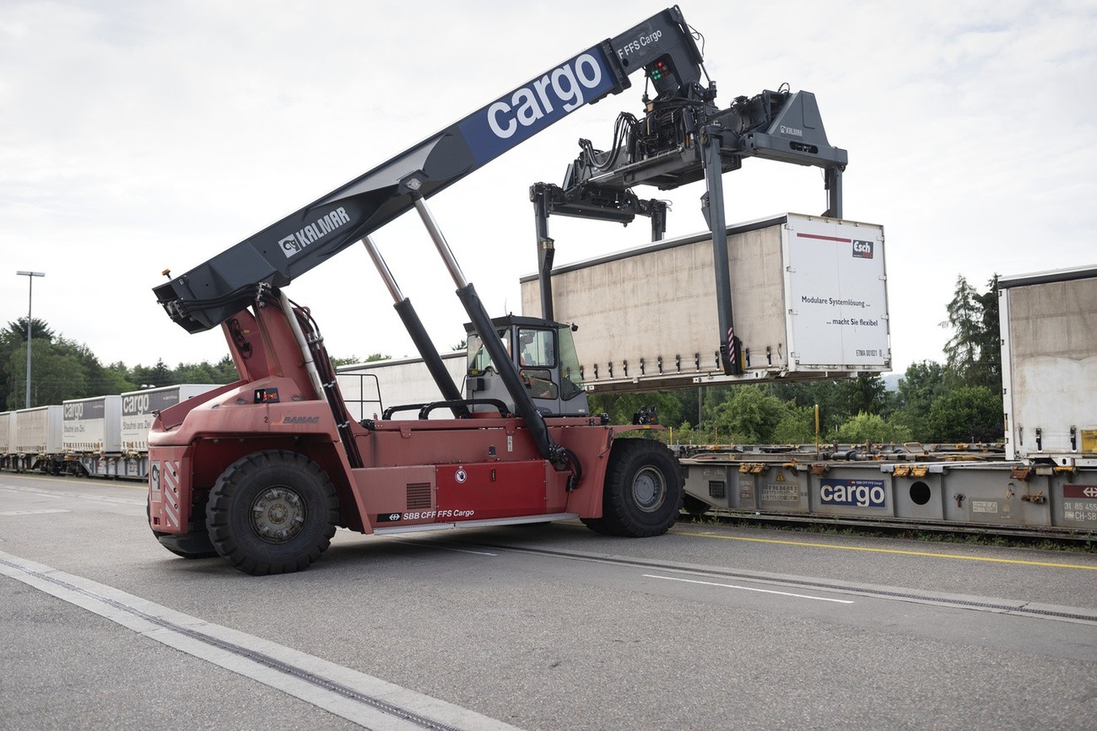 A mobile crane is used to unload containers from trucks onto the railway at the transhipment terminal of Swiss Federal Railways Cargo in Dietikon, Switzerland, on June 21, 2019. (KEYSTONE/Gaetan Bally ...