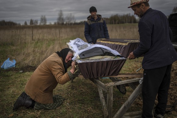 FILE - Nadiya Trubchaninova, 70, cries while holding the coffin of her son Vadym, 48, who was killed by Russian soldiers last March 30 in Bucha, during his funeral in the cemetery of Mykulychi, on the ...