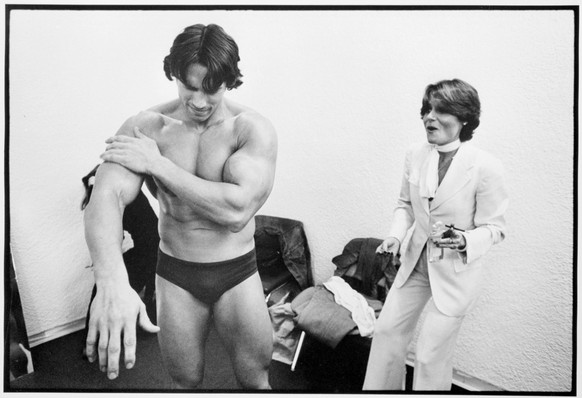 Arnold Schwarzenegger, the newly elected California governor, rubs baby oil on his arms while preparing for a public appearance during an exhibition on bodybuilding as art, at The Whitney Museum in Ne ...