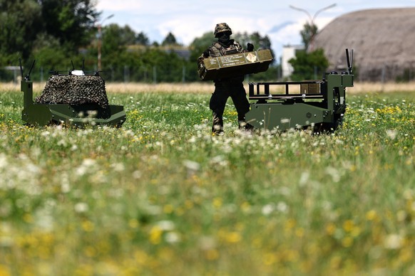 epa12253432 A soldier takes a box from a Gereon unmanned ground vehicle during the visit of the German defense minister at the Innovation Lab at the Bundeswehr Research Institute for Materials, Fuels  ...