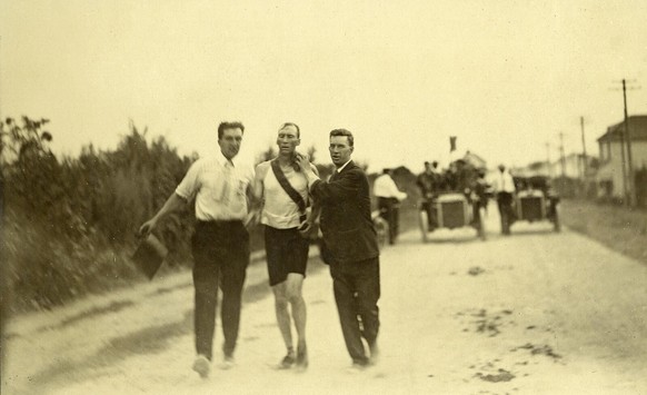 Hicks, au bord du supplice, soutenu par ses deux entraîneurs improvisés.