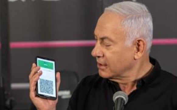 Le Premier ministre Benjamin Netanyahu visite un gymnase avec son carnet de vaccination numérique.