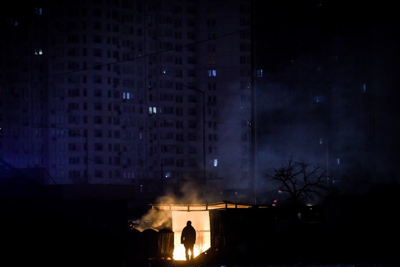 epaselect epa10335713 A man stands near burning garbage in front of an apartment building during a scheduled power cut in Kyiv (Kiev), Ukraine, 28 November 2022 (issued 29 November 2022). According to ...