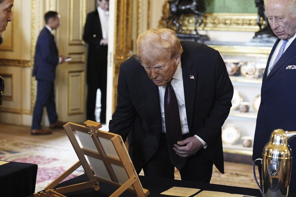 President Donald Trump, left, with Britain&#039;s King Charles III, view items on display during a visit to the Royal Collection exhibition, in the Green Drawing Room at Windsor Castle, in Windsor, En ...
