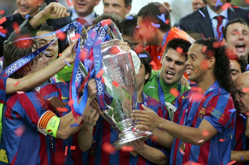 FC Barcelona's Ronaldinho (R) receives the Champions League trophy from his team-mate Carles Puyol (L) after the UEFA Champions League soccer final against Arsenal FC at the Stade de France in St ...