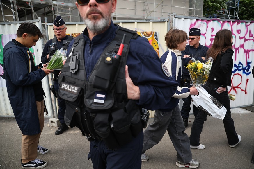 epa12054188 Police members guard students who arrive with flowers for a gathering at the Notre-Dame de Toutes-Aides high school, where a student stabbed several teenagers the day before, in Nantes, Fr ...
