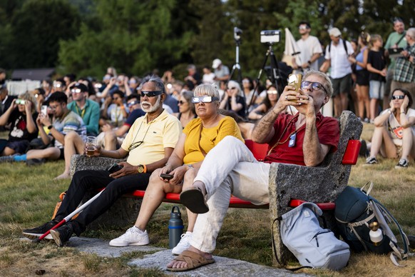People watch with their glasses when the moon obscures the sun during a partial solar eclipse, in Cardada over Locarno, Switzerland, Wednesday, August 12, 2026. Tonight, Switzerland witnesses its bigg ...