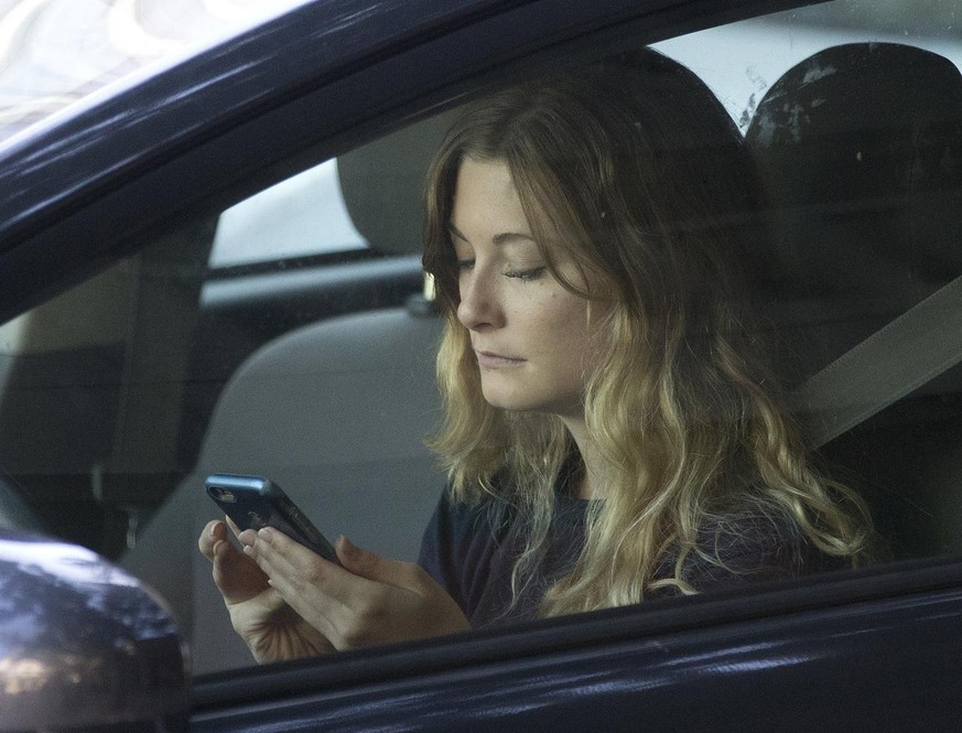 FILE - In this Wednesday, June 22, 2016, file photo, a driver uses her mobile phone while sitting in traffic in Sacramento, Calif. The government wants smartphone makers to lock out most apps when the ...
