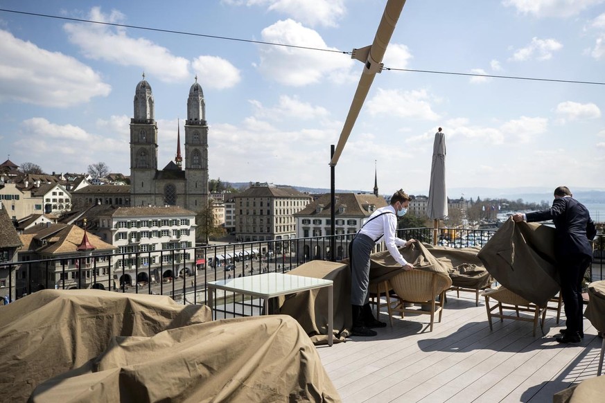 Mitarbeiter entfernen die Blachen von Tischen, Stuehlen und Schirmen am Freitag, 16. April 2021, auf der Terrasse &#039;The Nest&#039; vom Hotel Storchen in Zuerich. Am Montag, 19. April 2021, duerfen ...