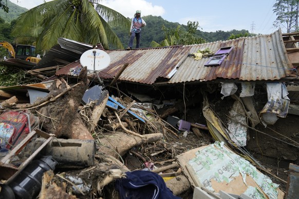 Marcelino Aringo stands on top of a damaged house after a landslide triggered by Tropical Storm Trami recently struck Talisay, Batangas province, Philippines, Saturday, Oct. 26, 2024 . (AP Photo/Aaron ...