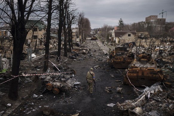 FILE - A Ukrainian serviceman walks amid destroyed Russian tanks in Bucha, on the outskirts of Kyiv, Ukraine, April 6, 2022. With Russian hopes for storming Kyiv and other major cities in northern Ukr ...