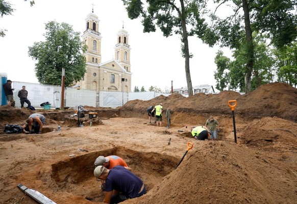 Workers are pictured at the excavation site during the exhumation of the remains of Soviet soldiers buried in the city center of Vievis, Lithuania, on July 20, 2026. A wartime grave-site outside Lithu ...