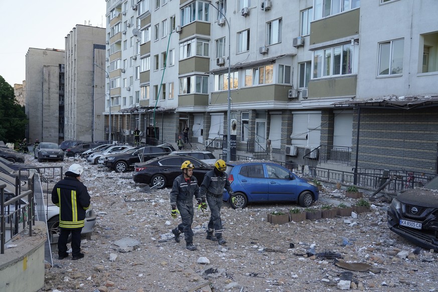 epa10662769 Rescue workers walk through rubble outside an apartment building after it was damaged during a drone strike in Kyiv (Kiev), Ukraine, 30 May 2023, amid the Russian invasion. At least one pe ...