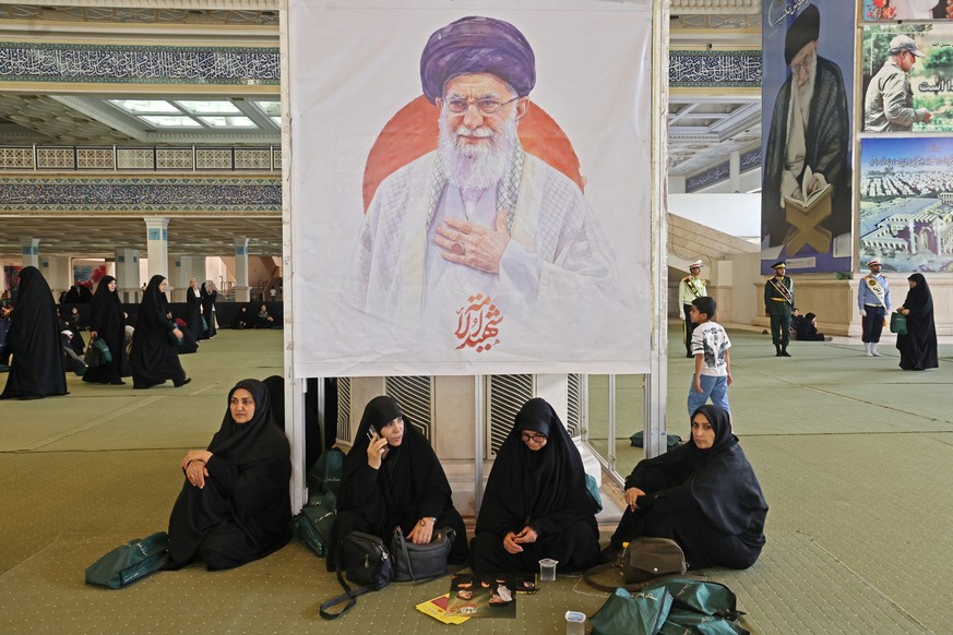 Iranian women sit infront of an image of the late assassinated supreme leader Ali Khamenei, as they gather at Imam Khomeini Mosque (Mosalla) to commemorate those killed in former wars and also those k ...