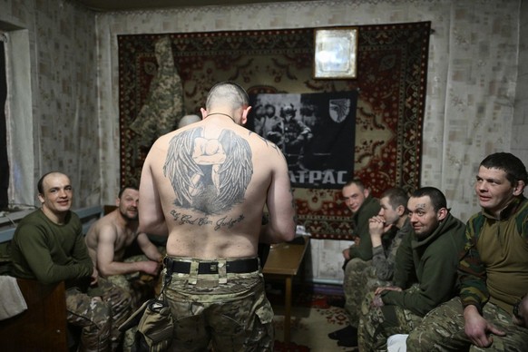 Servicemen of the Alkatraz special rifle battalion of the 93rd Motorized Brigade, former prisoners who volunteered to defend Ukraine, show their tattoos as they gather for a squad meeting at an undisc ...
