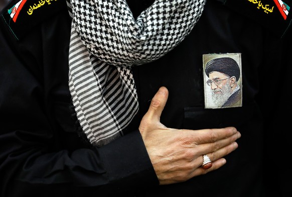 epa12785901 (FILE) - An Iranian worshipper gestures next to a picture of Iranian Supreme Leader Ayatollah Ali Khamenei on his chest as he takes part in a Friday prayer ceremony at Imam Khomeini mosque ...