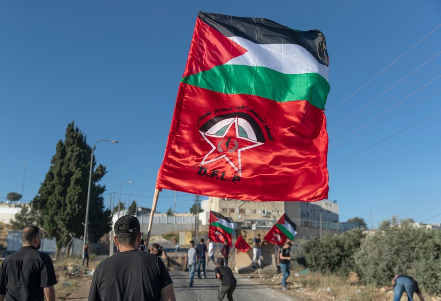 FILE - Palestinian protesters fly Palestinian flags and flags of the Democratic Front for the Liberation of Palestine, DFLP, during clashes with Israeli soldiers at the entrance the Jewish settlement  ...