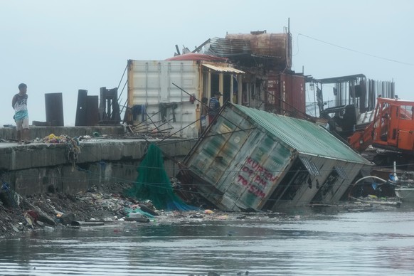 A man walks beside a container van that was toppled due to strong winds and waves caused by Typhoon Fung-wong on Monday, Nov. 10, 2025, along a coastal town in Navotas, Philippines. (AP Photo/Aaron Fa ...