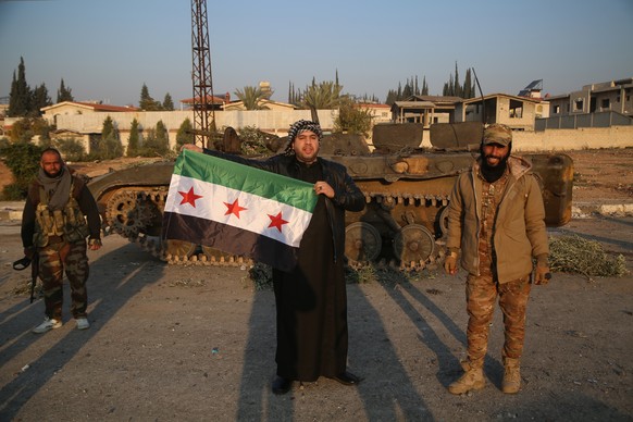 epa11760249 A man (C) holds a flag of the Syrian opposition after Syrian opposition forces entered the city of Hama, Syria, 06 December 2024. Syrian opposition forces, led by the Islamist militant gro ...