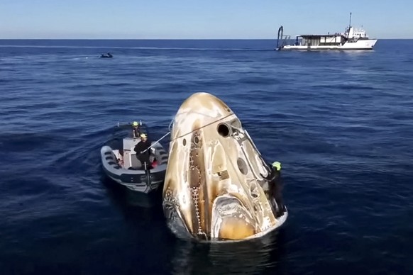epa11972860 A frame grab from live streamed NASA video of the SpaceX Crew Dragon capsule surrounded by recovery teams after splashing down off the coast Tallahassee, Florida, USA, 18 March 2025. Four  ...