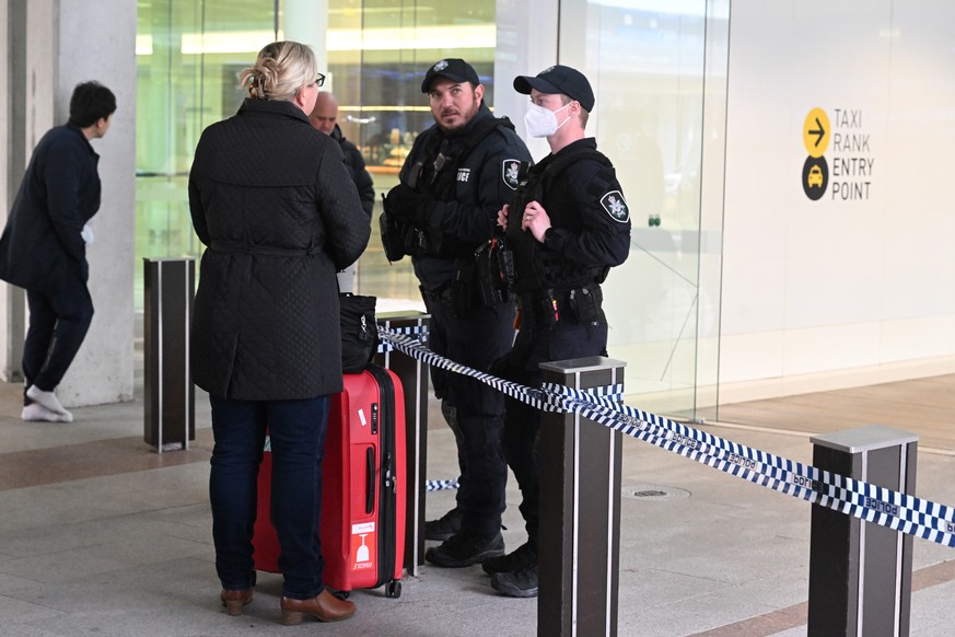 epa10120103 A passenger speaks to Australian Federal Police after a man fired at least three gunshots at Canberra Airport, in Canberra, Australia, 14 August 2022. The airport was evacuated and a man w ...