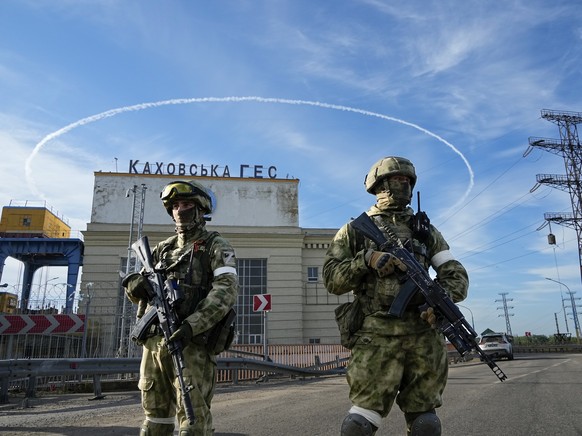FILE - Russian troops guard an entrance of the Kakhovka Hydroelectric Station, a run-of-the-river power plant on the Dnieper River in Kherson region, southern Ukraine, May 20, 2022. Despite getting bo ...