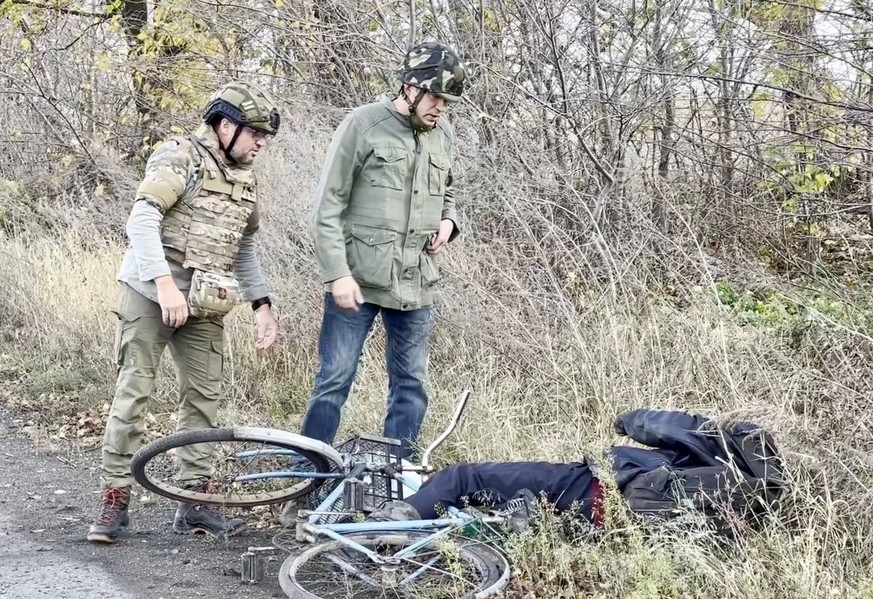 Un cycliste gît à côté de la route, au milieu de la zone de combat.