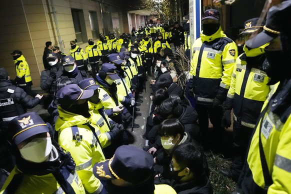 Police officers stand in front of supporters of impeached South Korean President Yoon Suk Yeol after they illegally climbed over a fence inside the Seoul Western District Court in Seoul, South Korea,  ...