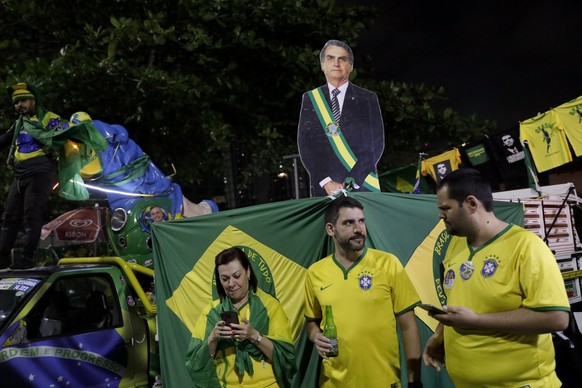 Supporters of Brazilian President Jair Bolsonaro, who is running for another term, follow partial results after general election polls closed outside his home in Rio de Janeiro, Brazil, Sunday, Oct. 2 ...