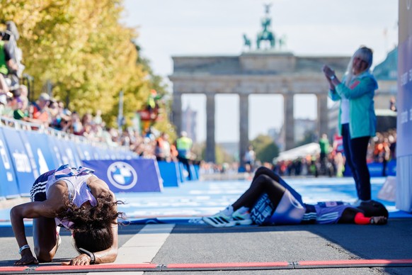 epa12395429 Second placed Dera Dida of Ethiopia (L) reacts after crossing the finish line while first placed Rosemary Wanjiru of Kenya (C) lies on the ground next to Berlin Senator for the Interior an ...