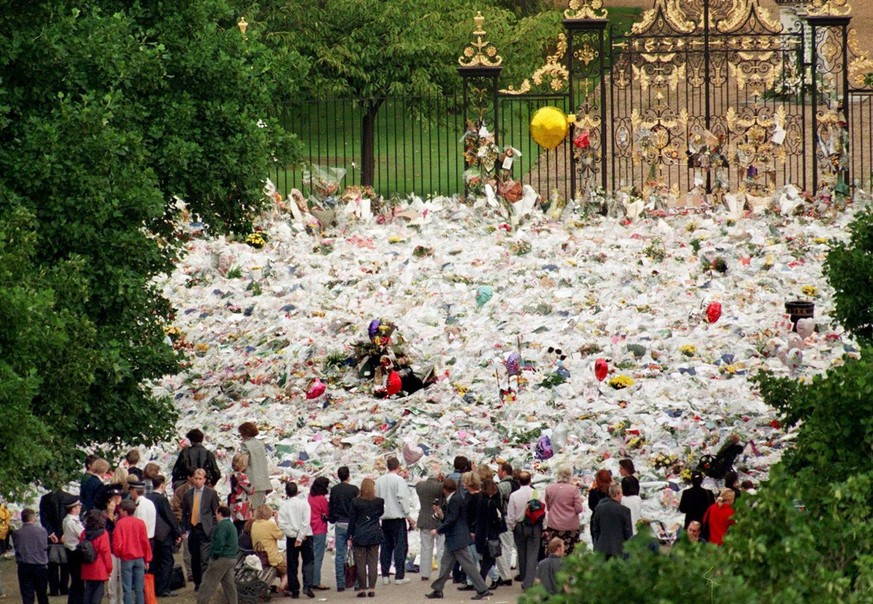 Picture dated 05 September 1997 of people gathering in front of a mass of flowers placed in front of Kensington Palace, Princess Diana&#039;s former home in London, on the eve of the Princess&#039;s f ...