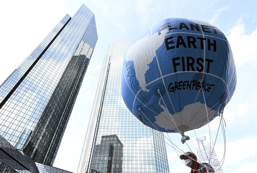 A demonstrator holds a balloon with the words &quot;Planet Earth First&quot; at the Fridays for Future central climate strike in Frankfurt, Germany, Friday Aug. 13, 2021, with Deutsche Bank headquarte ...