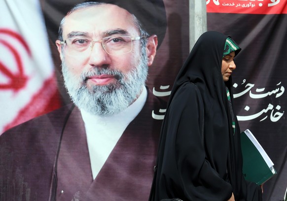epa12899720 A veiled Iranian woman walks past a picture of Irans Supreme Leader Mojtaba Khamenei on a street in Tehran, Iran, 19 April 2026. Tensions between the United States and Iran continue as th ...