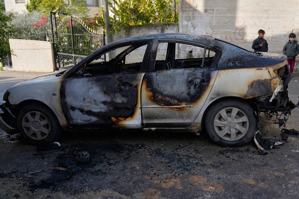 Children stay next to a vehicle that was torched during an Israeli settlers rampage early morning in the West Bank town of Ein Yabrud, Wednesday, Dec. 17, 2025. (AP Photo/Nasser Nasser)
Israel Palesti ...