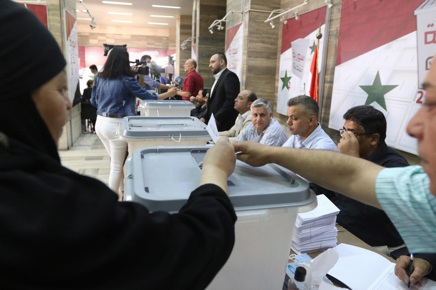epa09228257 A woman casts her vote at a polling station during the 2021 Syrian presidential election in Damascus, Syria, 26 May 2021. Syrians will choose one of three candidates, including current Pre ...