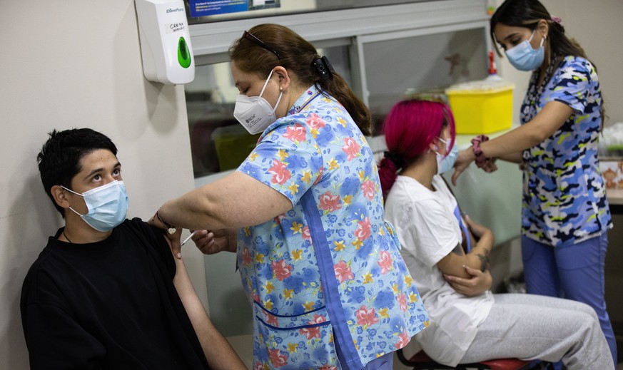 epa09677295 Two people receive a dose of the vaccine against Covid-19, at a vaccination center in Santiago, Chile, 10 January 2022. On 10 January, Chile becomes the second country in the world after I ...