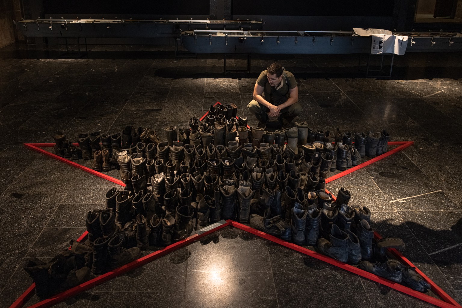 epa10112976 A man looks at boots that belonged to Russian soldiers as he visits the &#039;Ukraine Crucifixion&#039; exhibition at the National Museum of the History of Ukraine in the Second World War, ...