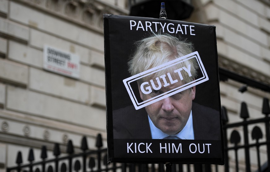 epa09887689 A protester holds up a placard of British Prime Minister Boris Johnson outside Downing Street in London, Britain, 13 April 2022. The Metropolitan Police have handed fines to British Prime  ...